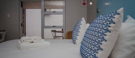 A hotel room with a bed, two pillows, a chair, and a table.