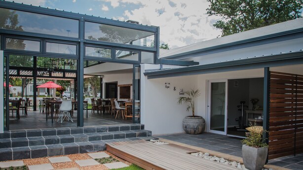 Une maison moderne dotée d’un patio, d’une salle à manger et d’une grande fenêtre donnant sur le jardin.