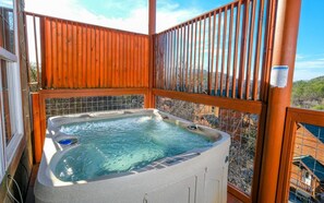 A hot tub on a balcony with a wooden railing and a view of the surrounding area.