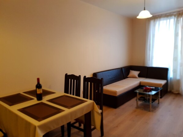 Una sala de estar con una mesa de comedor, dos sillas, un sofá y una mesa de centro.