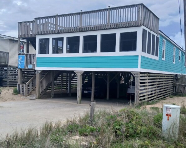 A two-story building with a wooden deck and a covered area. - Family & Pet Friendly Cottage --
Clean, cozy, and relaxing vibe! (Kitty Hawk)