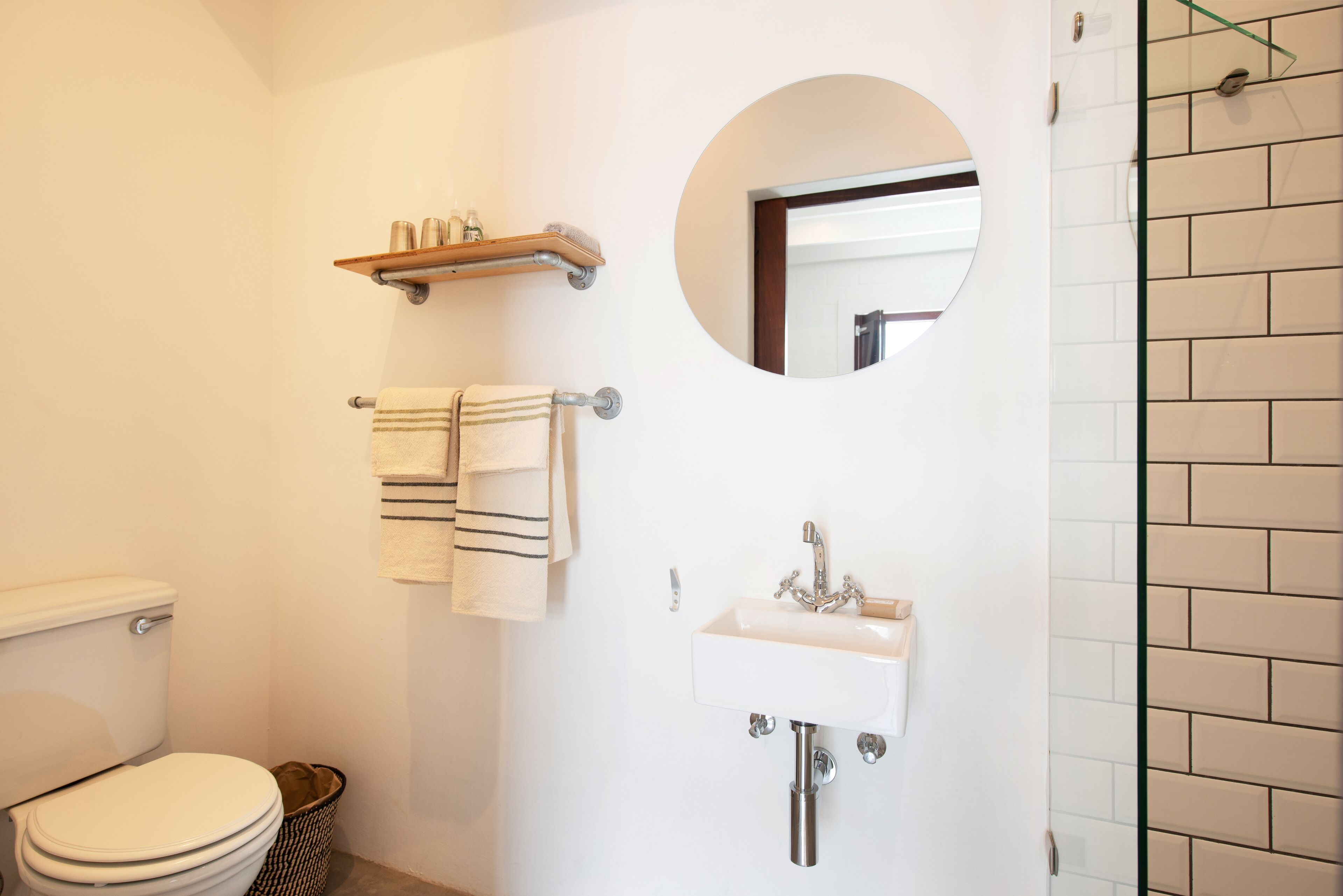 A bathroom with a toilet, sink, and a mirror.
