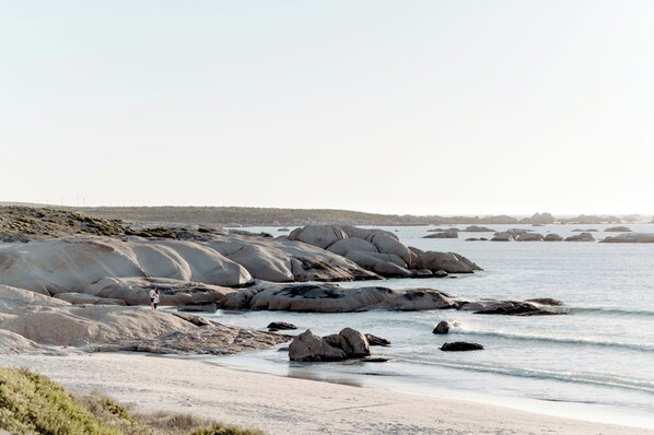 A coastal landscape with large boulders and a sandy beach. - Gonana Guesthouse (Paternoster)
