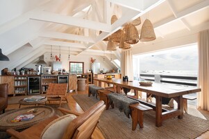 Un loft espacioso con techos altos, vigas a la vista y grandes ventanales con vista al océano.