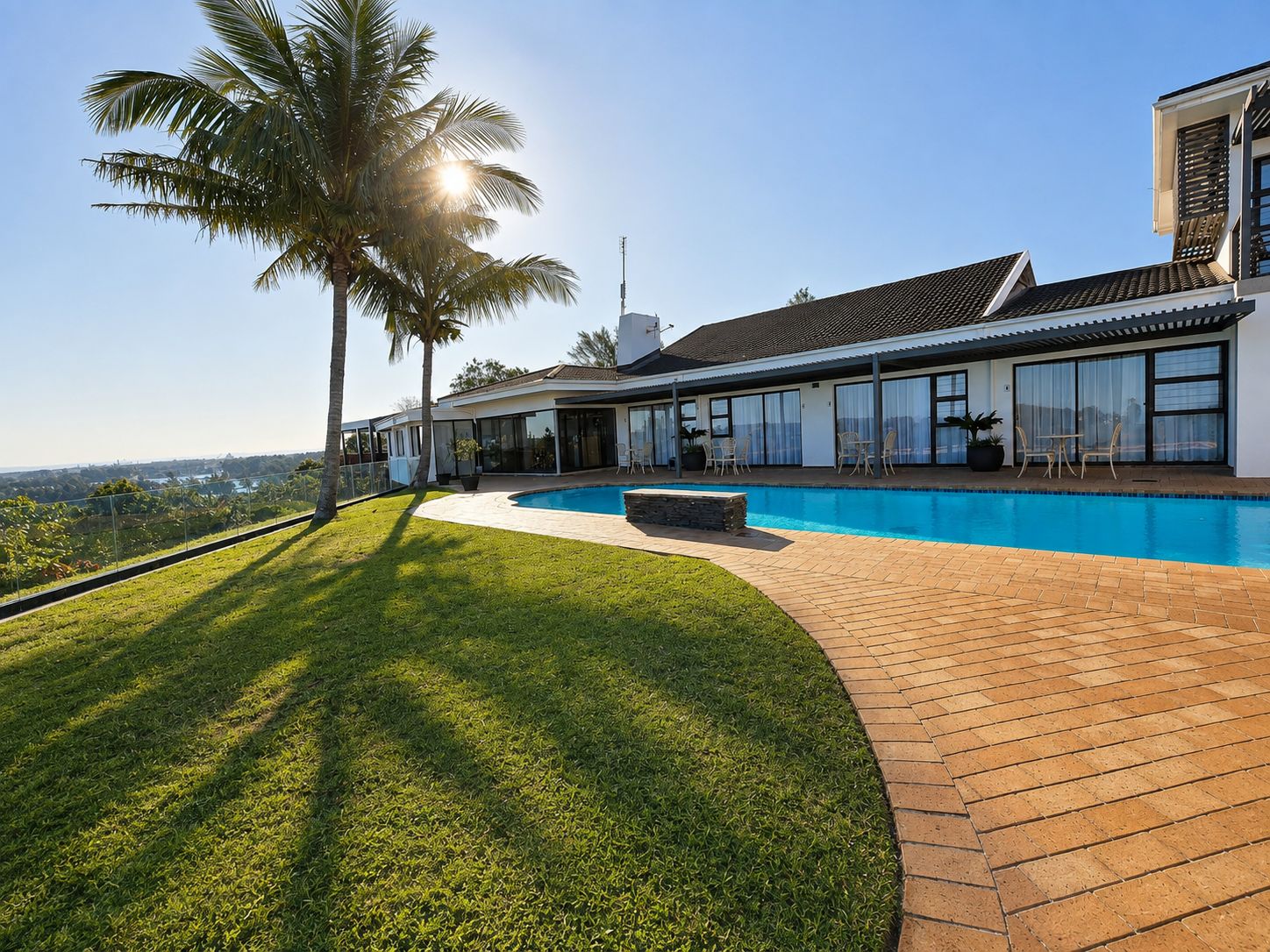 A modern house with a swimming pool, a covered patio, and a view of the landscape.