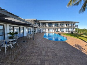 A hotel with a swimming pool, outdoor seating, and a view of the surrounding landscape. - The Ridge Guesthouse (Richards Bay)