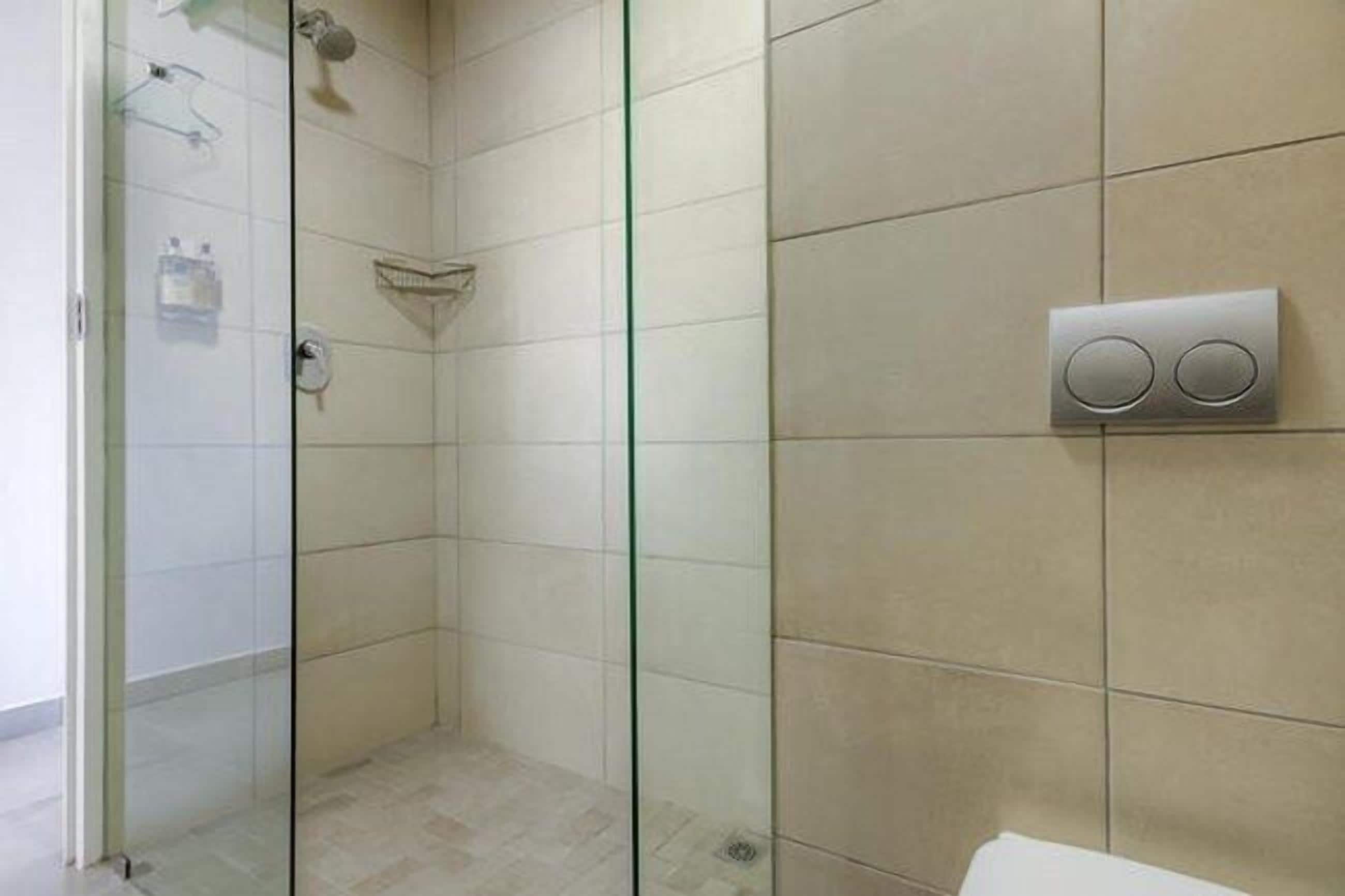 A bathroom with a glass shower enclosure, a toilet, and a wall-mounted bidet.