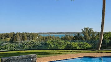 A swimming pool with a clear view of a lake and trees in the background.