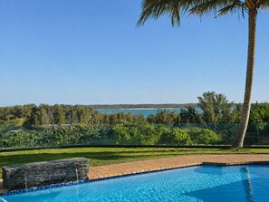 A swimming pool with a clear view of a lake and trees in the background. - The Ridge Guesthouse (Richards Bay)