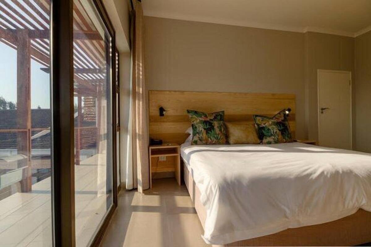 A bedroom with a large window, a wooden headboard, and two nightstands.