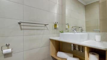 A modern bathroom with a large mirror, white sink, and a towel rack.