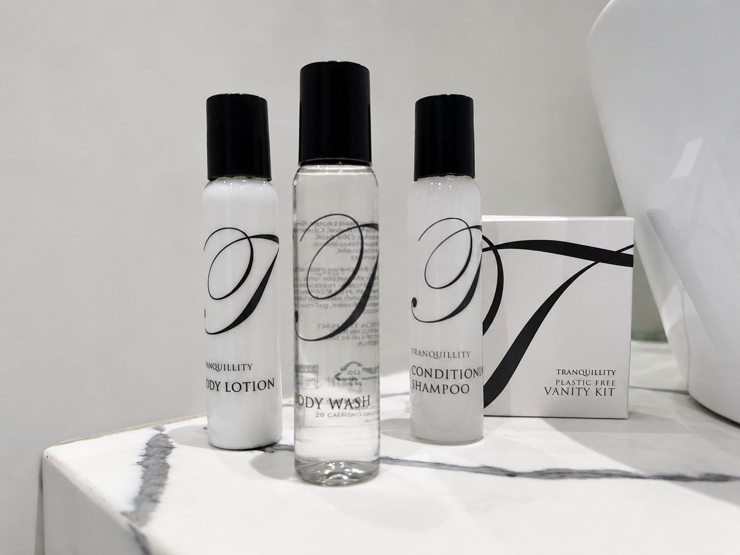 Un ensemble de produits de toilette comprenant une lotion pour le corps, un gel douche et un shampooing, ainsi qu’une trousse de toilette.