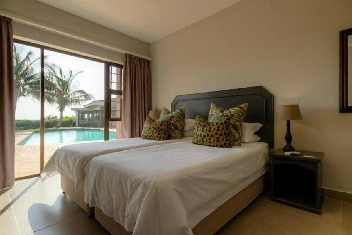 A hotel room with a large bed, a nightstand, and a view of a swimming pool.