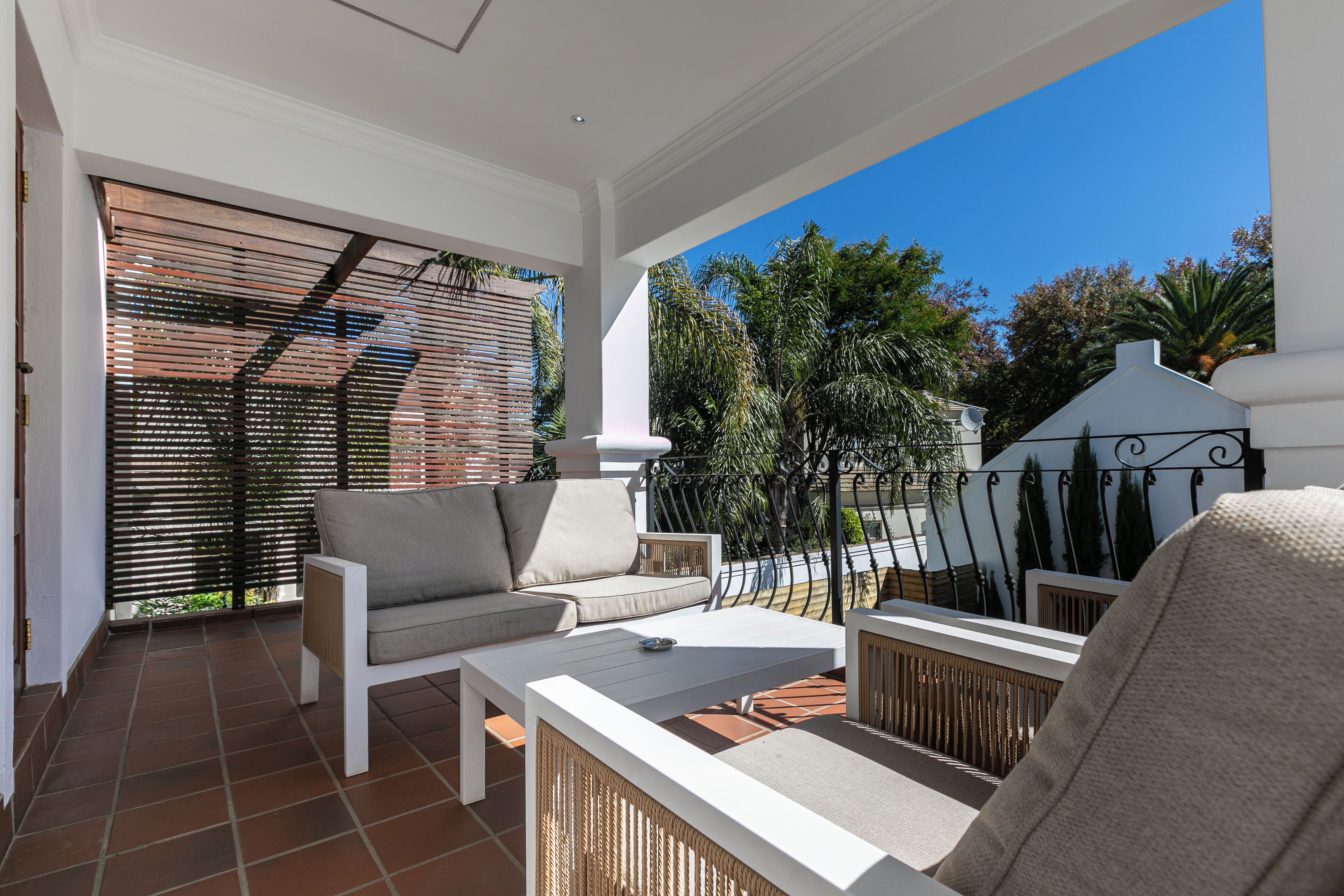 A balcony with a sofa, chairs, and a table.