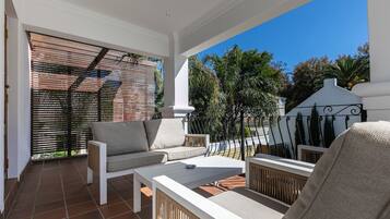 A balcony with a sofa, chairs, and a table.