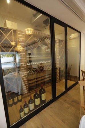 A wine cellar with shelves of wine bottles and a brick wall. - Zevenster Boutique Hotel (Germiston)