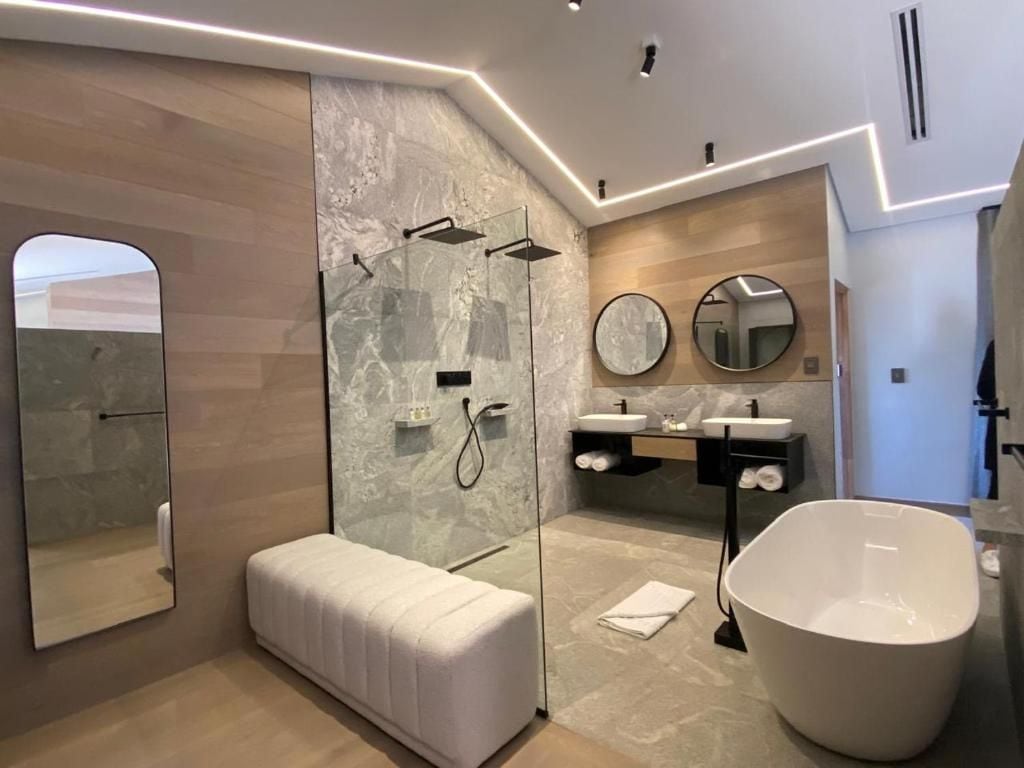 Un baño moderno con ducha envuelta en vidrio, una bañera independiente y un tocador con espejo.