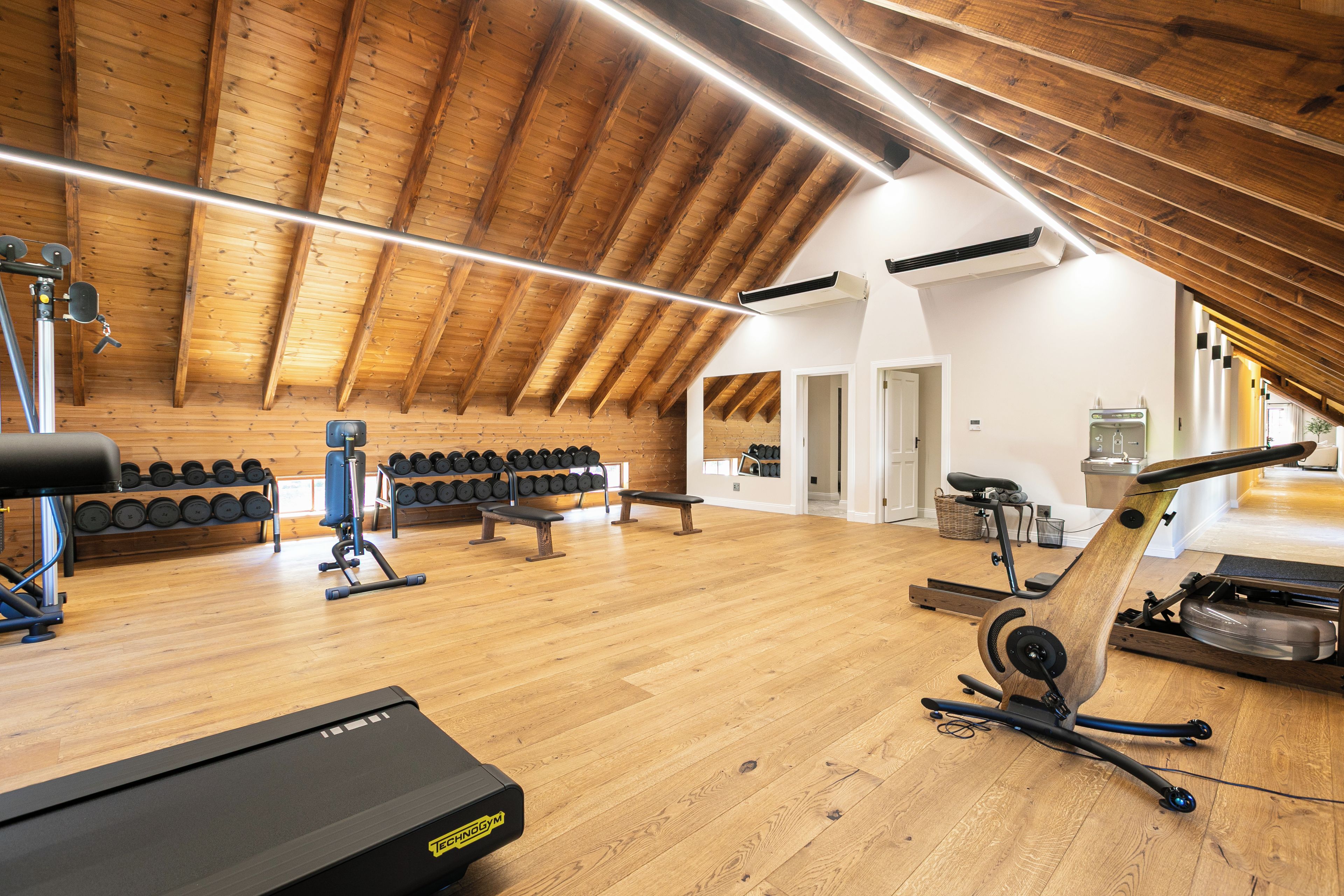 A gym with wooden beams, exercise equipment, and a treadmill.