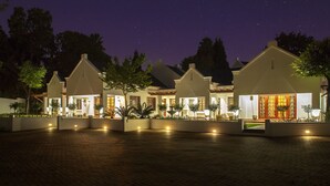 A row of modern houses with large windows and outdoor lighting, set against a night sky. - The Giglio Boutique Hotel (Germiston)