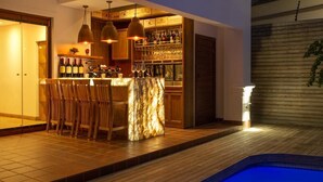 A bar area with wooden chairs, a marble counter, and hanging pendant lights. - The Giglio Boutique Hotel (Germiston)