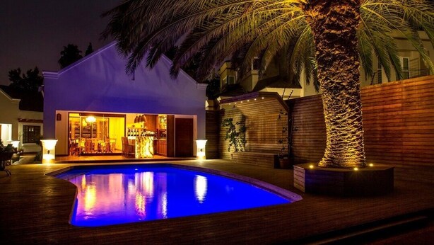 A modern house with a swimming pool, a bar area, and a palm tree. - The Giglio Boutique Hotel (Germiston)