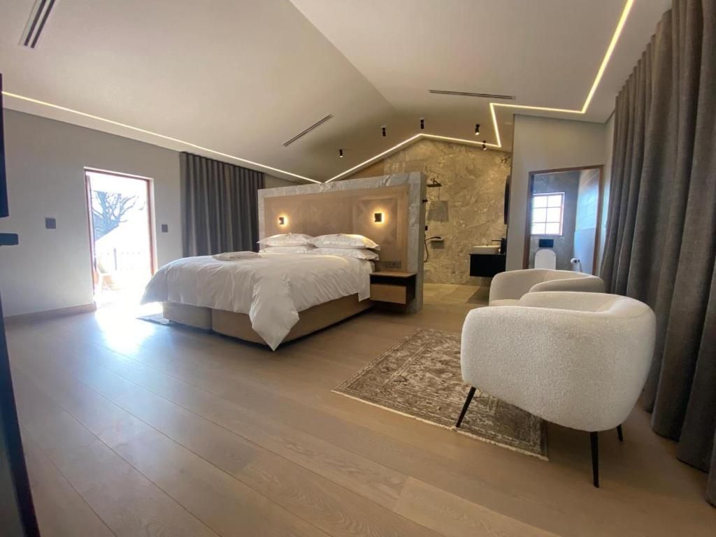 Un dormitorio moderno con una cama grande, un rincón de descanso y una pared decorativa de piedra.