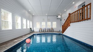 Ein Hallenbad mit einer Holztreppe und Stühlen an den Fenstern.