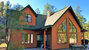 Eine Blockhütte mit großer Veranda, zahlreichen Fenstern und einem Steinkamin.