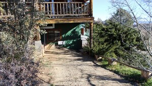 A cabin with a dirt path leading to a wooden deck and a sign indicating a park entrance. - Liberty Suite - Prescott Cabin Rentals (Prescott)