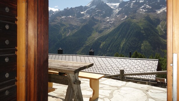 A wooden bench and table on a stone terrace with a mountain view. - Beautiful chalet in 3918 Lauchernalp, Wiler, Valais (Wiler (Lötschen))