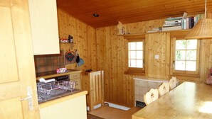 A wooden cabin interior with a kitchen area, dining table, and a window providing natural light. - Beautiful chalet in 3918 Lauchernalp, Wiler, Valais (Wiler (Lötschen))