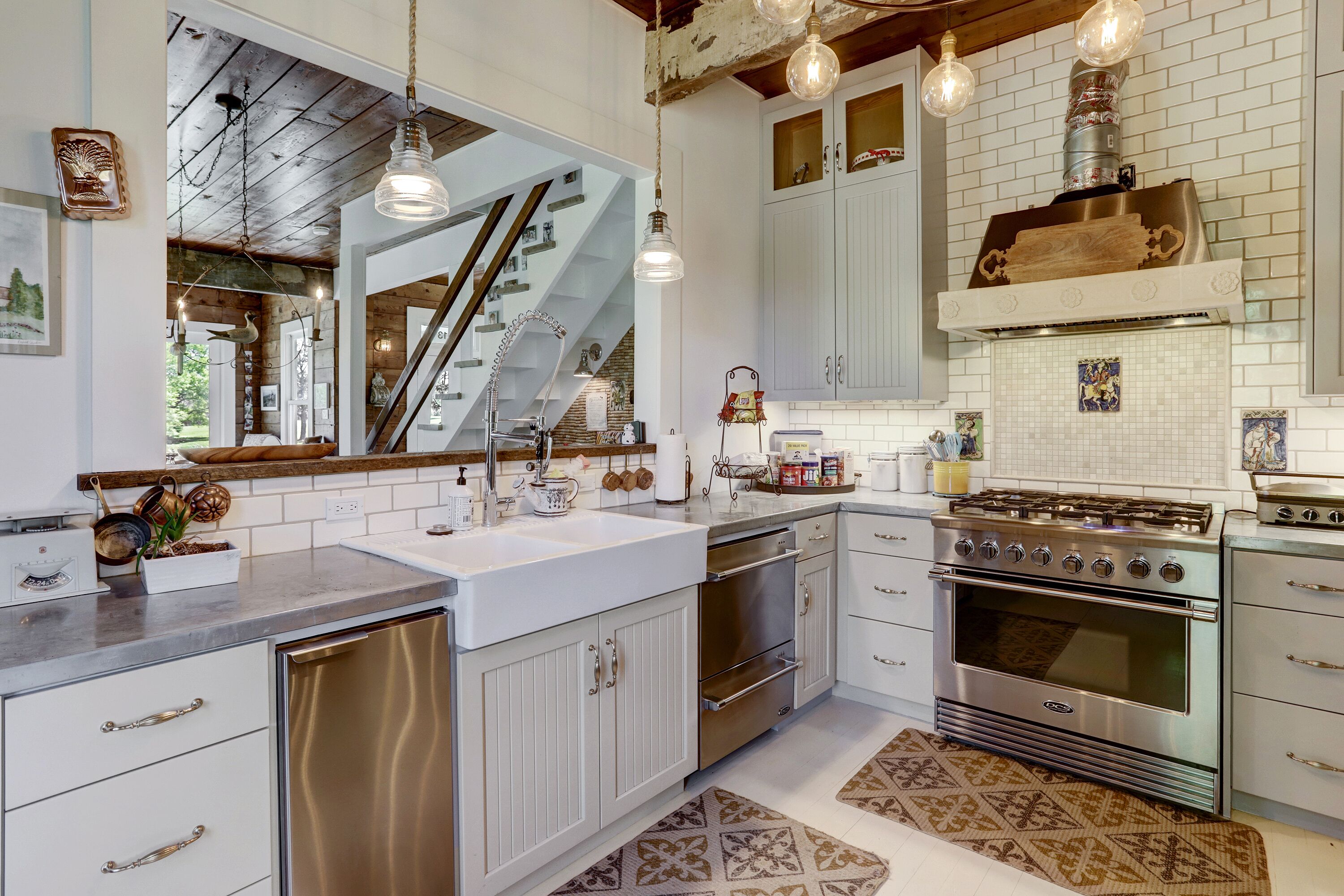A modern kitchen with stainless steel appliances, white cabinetry, and a wooden staircase.