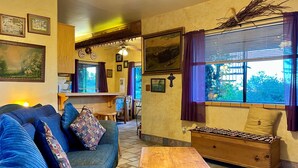 A cozy living room with a blue sofa, a wooden table, and a window with curtains.