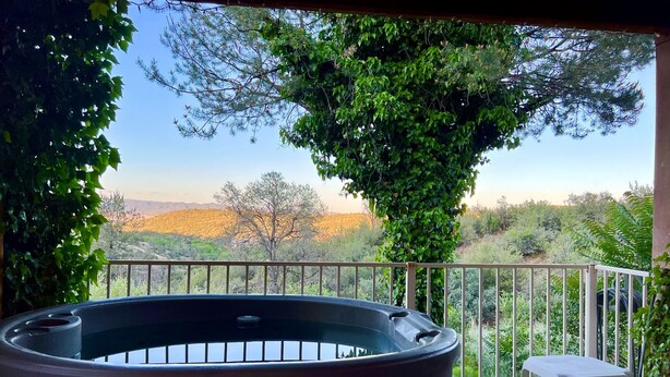 A hot tub on a wooden deck with a view of a mountainous landscape.