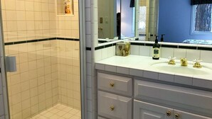 A bathroom with white tiled walls, a blue accent wall, a white sink with gold faucets, and a mirror above the sink.