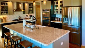 A modern kitchen with a central island, stainless steel appliances, and pendant lighting. - Longview Lodge - Prescott Cabin Rentals (Prescott)