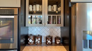 A kitchen with a stainless steel refrigerator, double doors with glass panels, and a tiled backsplash. - Longview Lodge - Prescott Cabin Rentals (Prescott)