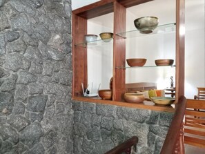 A stone wall with a wooden shelf displaying pottery. - Pousada dos Sinos (São João del Rei)