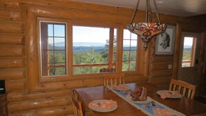 A wooden cabin dining room with a large table, chairs, and a chandelier. - Lone Pine Lodge - Prescott Cabin Rentals (Prescott)