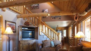 A log cabin interior with a wooden staircase, leather furniture, and a fireplace. - Lone Pine Lodge - Prescott Cabin Rentals (Prescott)