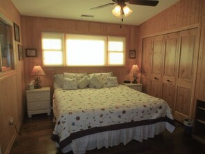 A bedroom with a bed, two bedside tables, a ceiling fan, and a window with blinds. - Western Pines Cottage - Prescott Cabin Rentals (Prescott)