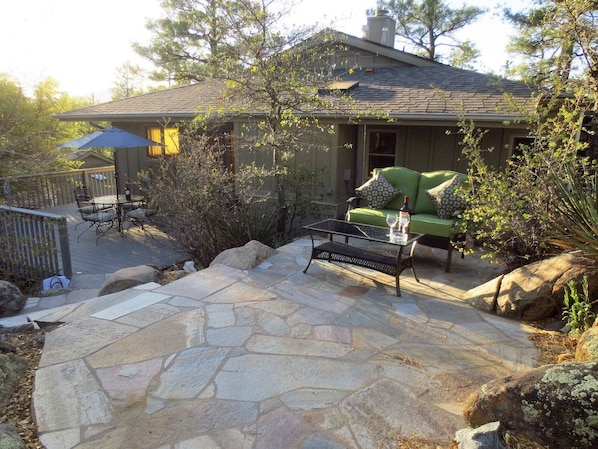 A house with a patio area featuring a stone floor, outdoor furniture, and a green sofa.