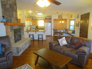 A living room with a fireplace, leather sofa, and a wooden coffee table. - Western Pines Cottage - Prescott Cabin Rentals (Prescott)