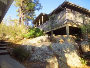 A two-story building with a balcony, surrounded by trees and rocks. - Western Pines Cottage - Prescott Cabin Rentals (Prescott)
