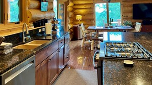 A log cabin interior with a kitchen, dining area, and a fireplace. - Timbertrail Lodge - Prescott Cabin Rentals (Prescott)