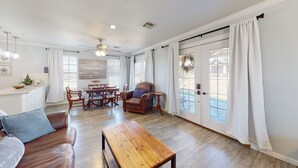 Un salon spacieux avec une table basse en bois, un canapé en cuir et un coin repas comprenant une table et des chaises.