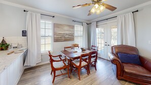 Un coin repas avec une table et des chaises en bois, un canapé en cuir marron et un ventilateur de plafond.