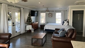 Un salon spacieux avec un grand lit, des canapés en cuir, une table basse en bois et un sapin de Noël.