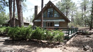 Eine Lodge mit großem Schornstein, einer Veranda und einer Steinsäule.