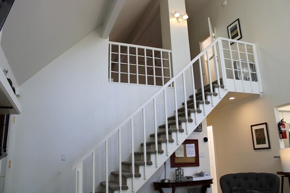 A staircase with white railings and carpeted steps leading to an upper floor.